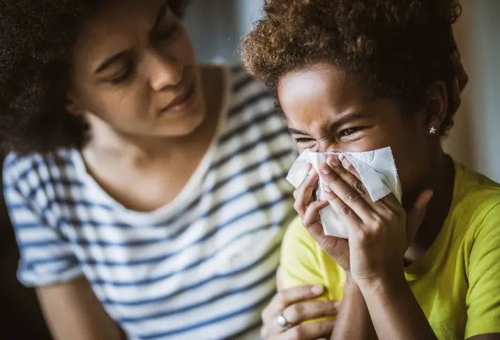 young child sneezing into a tissue