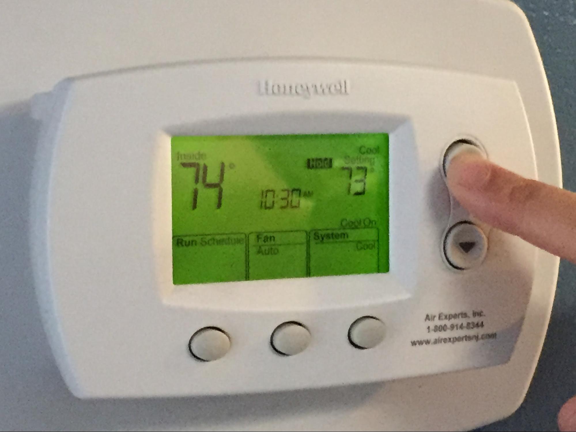 person putting the hand on a thermostat